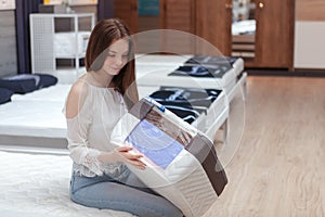 Young woman choosing new orthopedic bed