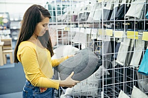 Young woman choosing pillow in the store