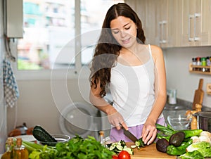 Young woman chopping vegetables at home kitchen