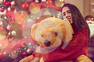 Young woman with Christmas gift.Girl hugs teddy bear present