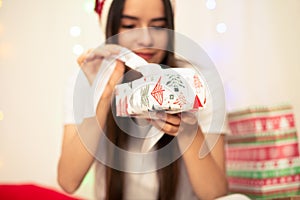 Young woman on Christmas morning opens gifts for the new year