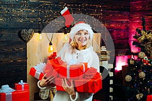 Young woman with christmas present boxes in front of christmas tree. Cheerful young woman wearing christmas costume over