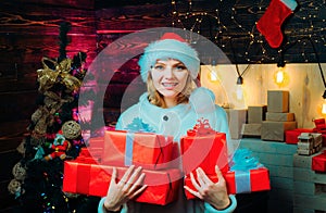 Young woman with christmas present boxes in front of christmas tree. Young woman wink. Funny christmas girl. Crazy