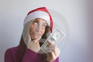 Young woman with Christmas red hat holding one dollar bill with frustration expression