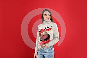 Young woman in Christmas sweater on red background