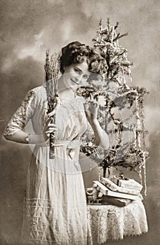 Young woman with christmas tree and gifts. Antique picture