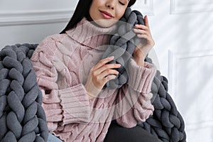 Young woman with chunky knit blanket on sofa at home, closeup