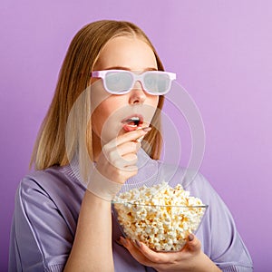 Young woman in cinema glasses watching 3d movie in cinema. Smiling teenager girl movie viewer in glasses eating popcorn 