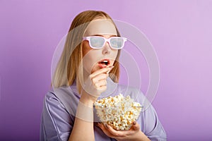 Young woman in cinema glasses watching 3d movie in cinema. Smiling teenager girl movie viewer in glasses eating popcorn