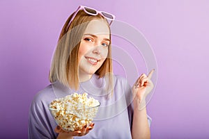 Young woman in cinema glasses watching 3d movie. Smiling teenager girl movie viewer in glasses with popcorn show with your hand on