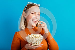 Young woman in cinema glasses watching 3d movie. Smiling teenager girl movie viewer in glasses eats popcorn with copy