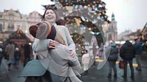 Young woman circling around on square in european town. Two girls laughing and having a good time in christmas fare
