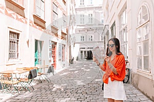 Young woman with a city map in city. Travel tourist girl with map in Vienna outdoors during holidays in Europe.