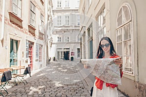 Young woman with a city map in city. Travel tourist girl with map in Vienna outdoors during holidays in Europe.