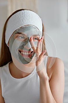 Young woman with clay facial cosmetology mask