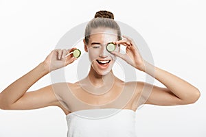 Young woman with clay facial mask holding cucumber slices isolated on white background