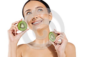 Young woman with clean radiant skin showing kiwi halves, on white background, beauty and skin care concept