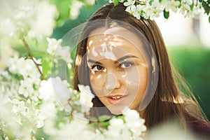 Young woman with clean skin near a blooming apple tree. gentle portrait of girl in spring park.