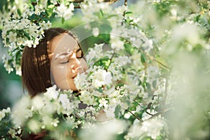 Young woman with clean skin near a blooming apple tree. gentle portrait of girl in spring park.