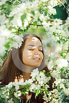 Young woman with clean skin near a blooming apple tree. gentle portrait of girl in spring park.