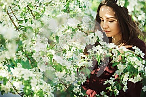 Young woman with clean skin near a blooming apple tree. gentle portrait of girl in spring park.