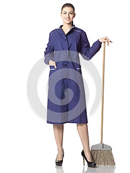 A young woman-cleaner stands with a broom in a blue robe.