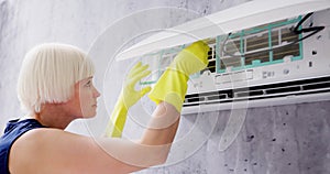 Young Woman Cleaning Air Conditioning System