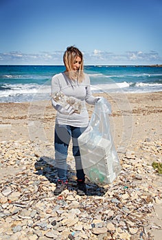 Young woman cleaning beach area from plastic