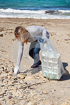 Young woman cleaning beach area from plastic