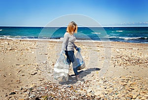 Young woman cleaning beach area from plastic