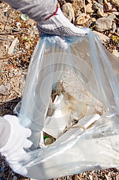 Young woman cleaning beach area and showing plastic in a bag