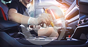 Young woman cleaning the car interior using a special brush with foam