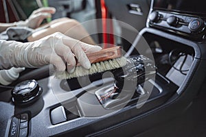 Young woman cleaning the car interior using a special brush with foam