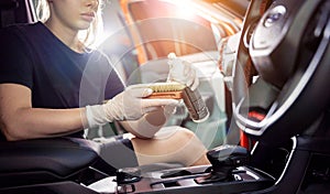 Young woman cleaning the car interior using a special brush with foam