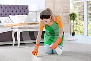 Young woman cleaning carpet with brush