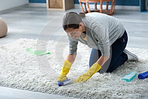 Young woman cleaning carpet at home