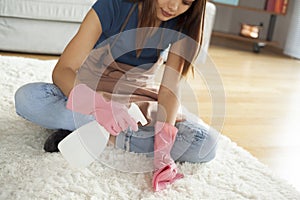 Young woman cleaning carpet in room