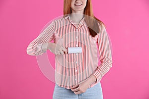 Young woman cleaning clothes with lint roller on pink background, closeup