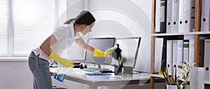 Woman Cleaning Computer Monitor In Office