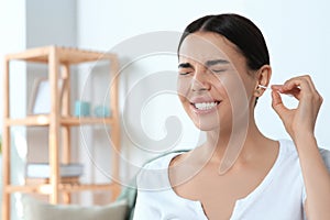 Young woman cleaning ear with cotton swab at home