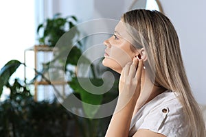 Young woman cleaning ear with cotton swab at home. Space for text