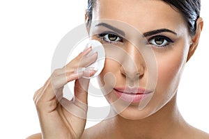 Young woman cleaning face with cotton pad