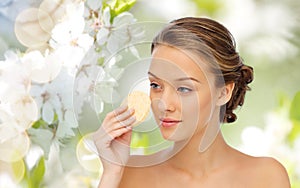 Young woman cleaning face with exfoliating sponge photo