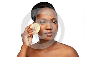 Young woman cleaning face with exfoliating sponge photo