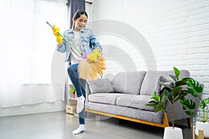 Young woman cleaning floor at home doing chores. She uses a broom instead of a guitar