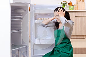 The young woman cleaning fridge in hygiene concept