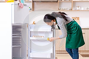 Young woman cleaning fridge in hygiene concept