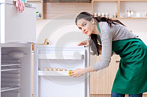 The young woman cleaning fridge in hygiene concept