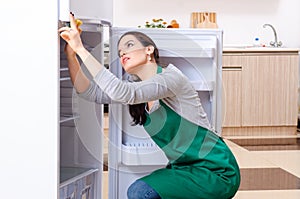 Young woman cleaning fridge in hygiene concept