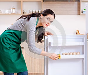 Young woman cleaning fridge in hygiene concept